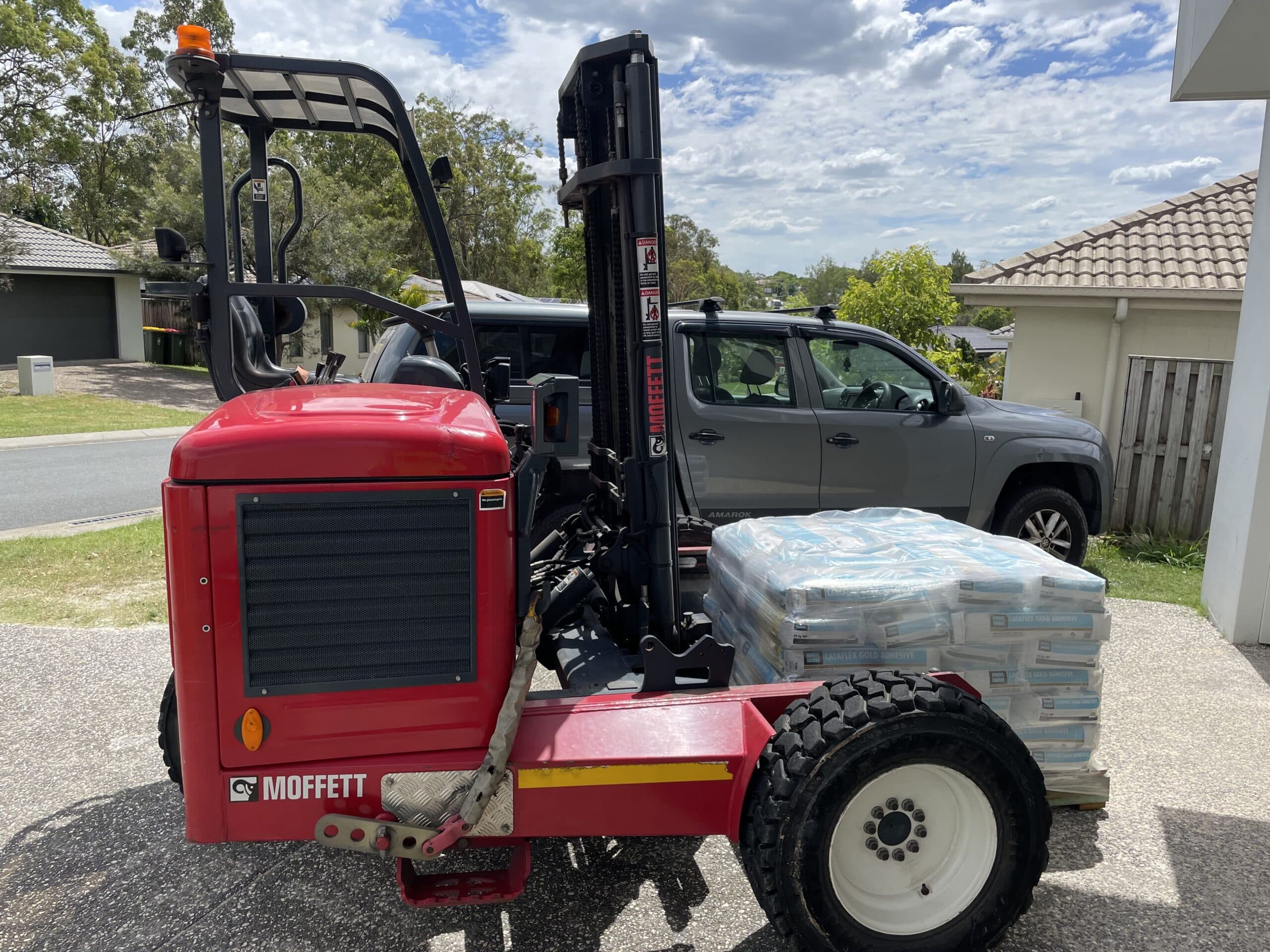 Red Moffett forklift unloading pallets at a residential site